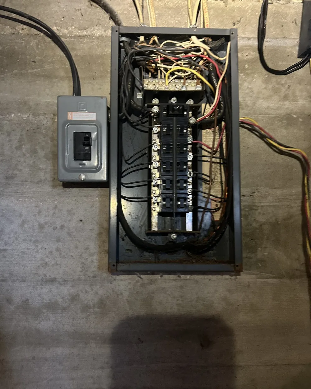 Old rusted electrical panel with tangled cloth-insulated wiring before replacement by Freedom Electric