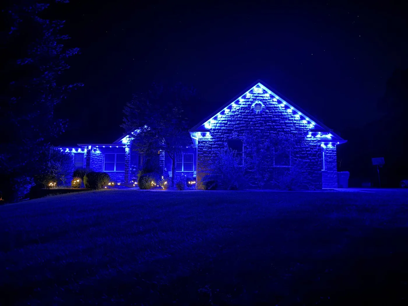 The same permanent eave lighting system set to blue for game day, installed by Freedom Electric
